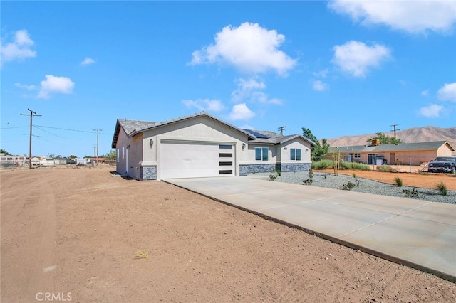 10533 Mohawk Rd, Apple Valley, CA 92308 - single story home with solar panels, concrete driveway, an attached garage, stone siding, and stucco siding