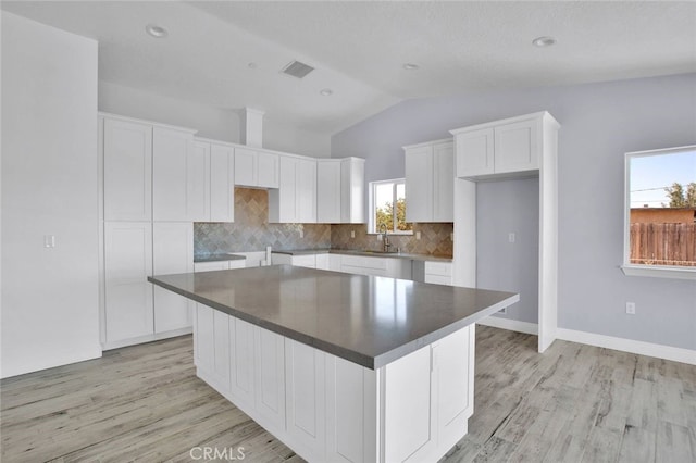 10533 Mohawk Rd, Apple Valley, CA 92308 - kitchen featuring lofted ceiling, white cabinetry, tasteful backsplash, light wood-style flooring, and a center island