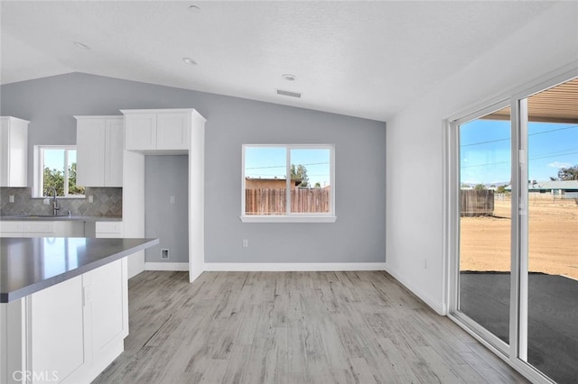10533 Mohawk Rd, Apple Valley, CA 92308 - kitchen featuring lofted ceiling, white cabinetry, light wood-type flooring, and backsplash