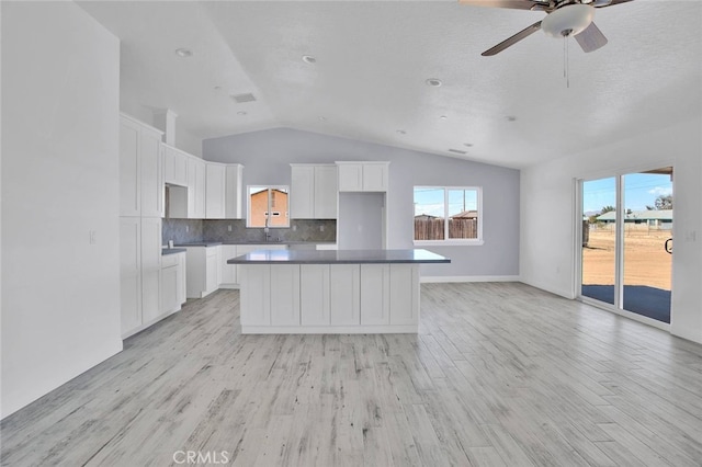 10533 Mohawk Rd, Apple Valley, CA 92308 - kitchen with decorative backsplash, lofted ceiling, light wood-style flooring, a center island, and white cabinets