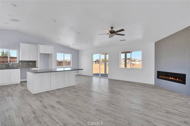 10533 Mohawk Rd, Apple Valley, CA 92308 - kitchen with lofted ceiling, open floor plan, light wood-type flooring, a large fireplace, and white cabinetry