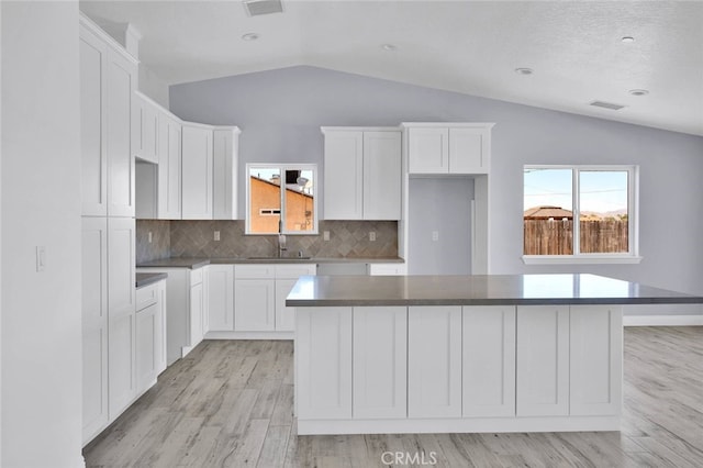 10533 Mohawk Rd, Apple Valley, CA 92308 - kitchen featuring vaulted ceiling, light wood-style flooring, a kitchen island, plenty of natural light, and decorative backsplash