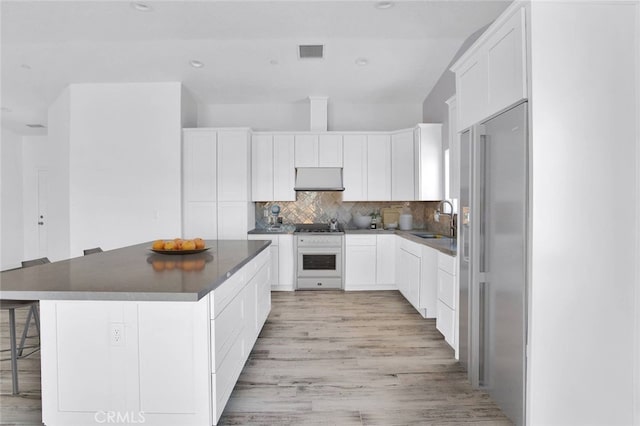 10533 Mohawk Rd, Apple Valley, CA 92308 - kitchen with wall oven, dark countertops, a center island, light wood-style floors, and decorative backsplash