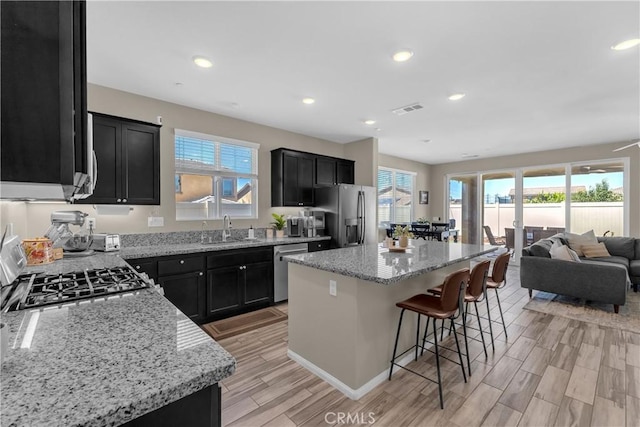 1511 Asteroid Way, Beaumont, CA 92223 - kitchen featuring appliances with stainless steel finishes, dark cabinets, healthy amount of natural light, a kitchen bar, and recessed lighting