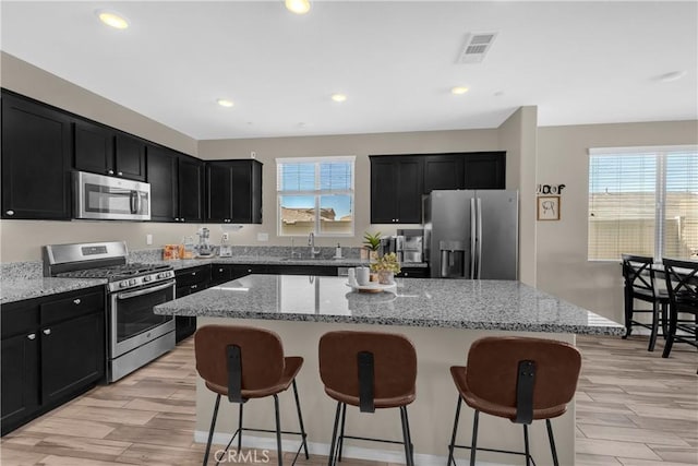 1511 Asteroid Way, Beaumont, CA 92223 - kitchen with stainless steel appliances, dark cabinets, a breakfast bar, and recessed lighting