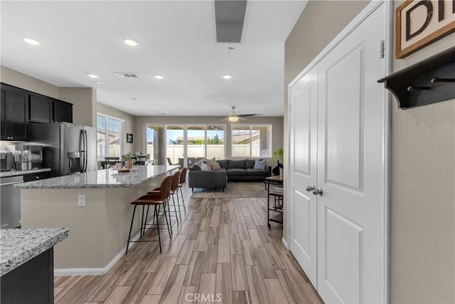 1511 Asteroid Way, Beaumont, CA 92223 - kitchen with stainless steel appliances, a kitchen bar, light wood-style flooring, a kitchen island, and recessed lighting