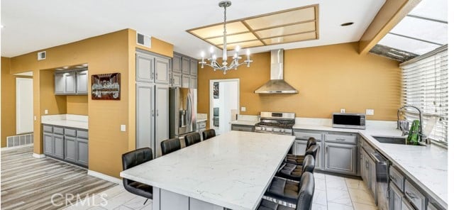 1020 La Salle Cir, Corona, CA 92879 - kitchen featuring wall chimney exhaust hood, gray cabinets, stainless steel appliances, and a kitchen bar