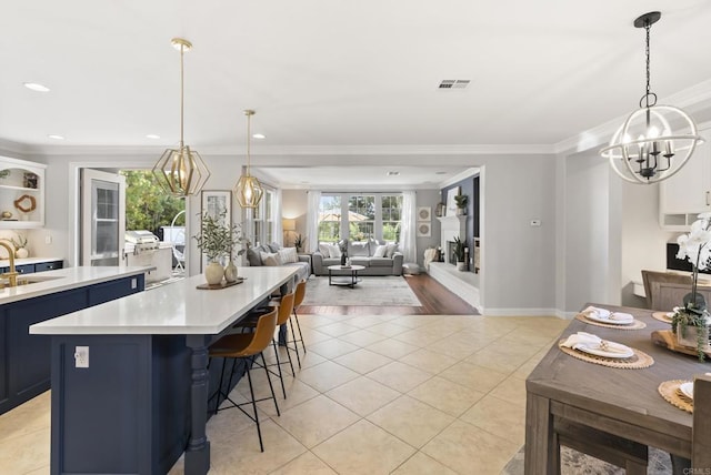6257 Alverton, Carlsbad, CA 92009 - kitchen featuring a chandelier, blue cabinets, light countertops, light tile patterned floors, and crown molding