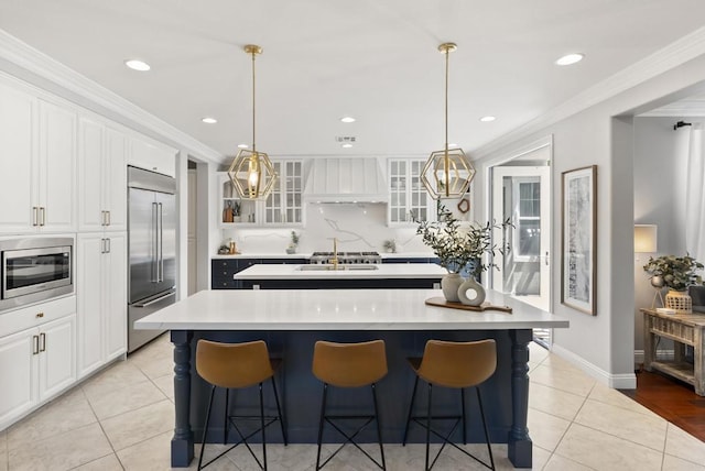 6257 Alverton, Carlsbad, CA 92009 - kitchen with built in appliances, custom range hood, an island with sink, light countertops, and light tile patterned flooring