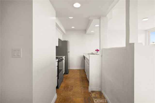 911 N Kings Rd Unit 310, West Hollywood, CA 90069 - kitchen with stainless steel electric range oven, white cabinetry, recessed lighting, dark stone finish floors, and light countertops