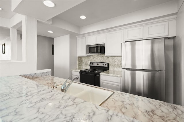 911 N Kings Rd Unit 310, West Hollywood, CA 90069 - kitchen with freestanding refrigerator, built in microwave, black electric range, tasteful backsplash, and white cabinetry