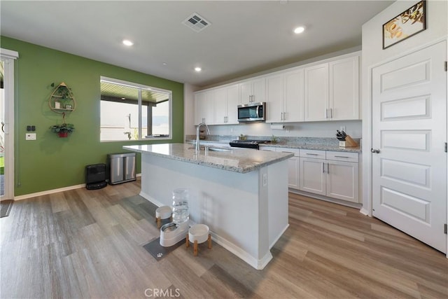 19465 Brush Creek Way, Lake Elsinore, CA 92532 - kitchen featuring stainless steel microwave, light wood-style floors, white cabinets, gas stove, and recessed lighting