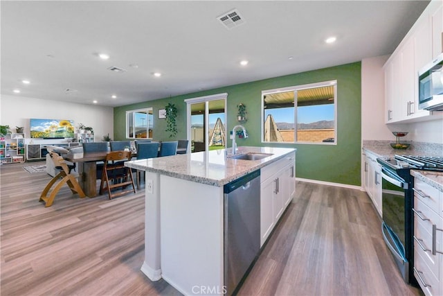19465 Brush Creek Way, Lake Elsinore, CA 92532 - kitchen with appliances with stainless steel finishes, white cabinetry, a center island with sink, light wood-style flooring, and recessed lighting