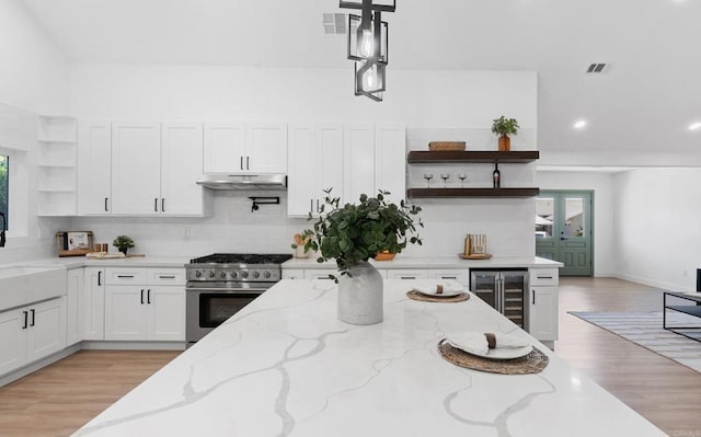 5122 Coban St, San Diego, CA 92114 - kitchen with open shelves, high end stainless steel range oven, wine cooler, white cabinets, and under cabinet range hood