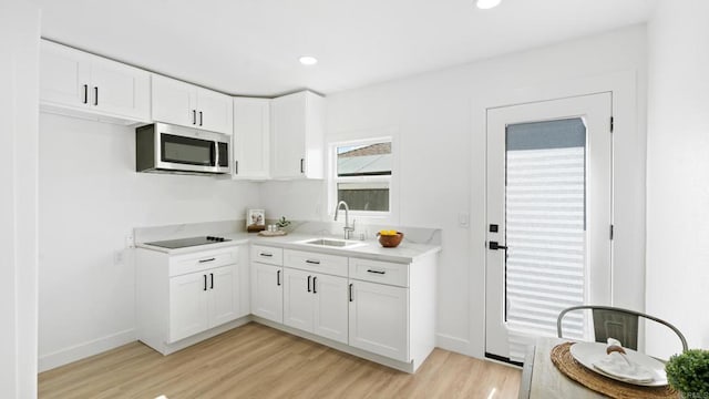 5122 Coban St, San Diego, CA 92114 - kitchen with stainless steel microwave, light wood finished floors, light countertops, white cabinets, and recessed lighting