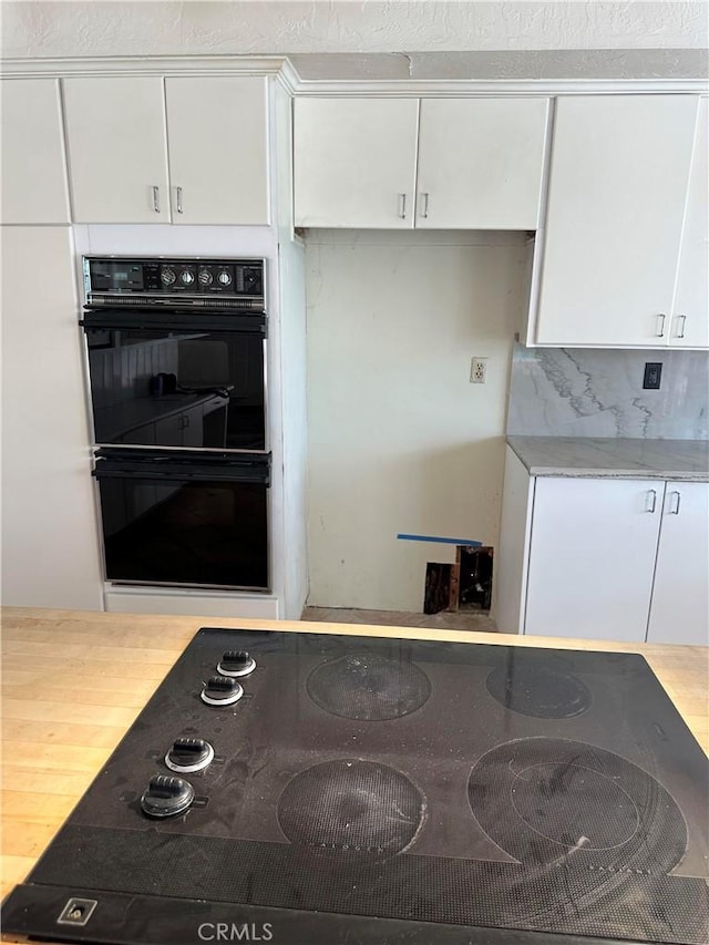 23135 Park Contessa, Calabasas, CA 91302 - kitchen with black appliances, white cabinetry, light countertops, decorative backsplash, and wood finished floors