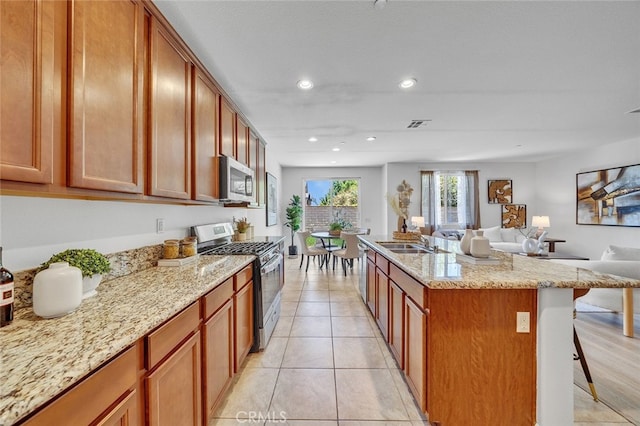 9370 Bistro Pl, Rancho Cucamonga, CA 91730 - kitchen featuring appliances with stainless steel finishes, a kitchen bar, recessed lighting, open floor plan, and light stone countertops