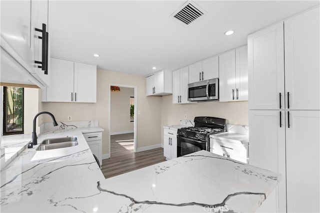 36647 Apache Plume Dr, Palmdale, CA 93550 - kitchen featuring black gas stove, stainless steel microwave, wood finished floors, white cabinetry, and recessed lighting