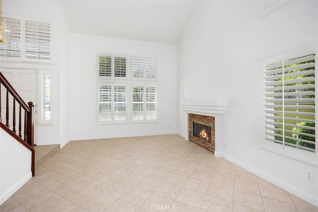 15 Havre Ct, Lake Forest, CA 92610 - unfurnished living room featuring plenty of natural light, a glass covered fireplace, stairway, high vaulted ceiling, and light tile patterned floors