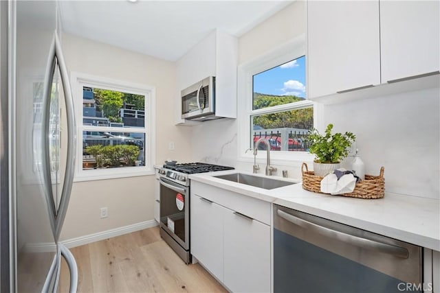 2961 Rounsevel, Laguna Beach, CA 92651 - kitchen featuring appliances with stainless steel finishes, modern cabinets, light wood-type flooring, and white cabinetry