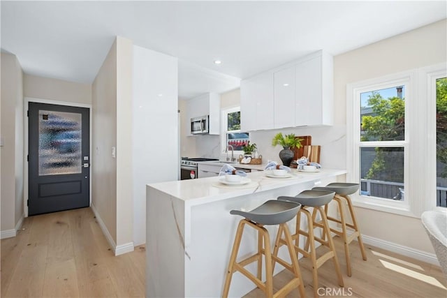 2961 Rounsevel, Laguna Beach, CA 92651 - kitchen featuring stainless steel appliances, light wood-style flooring, light countertops, a kitchen bar, and recessed lighting