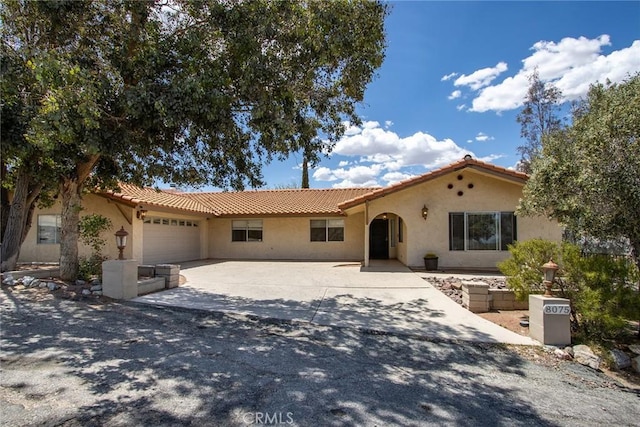 8075 Quail Trl, Yucca Valley, CA 92284 - mediterranean / spanish-style house with stucco siding, an attached garage, a tiled roof, and driveway