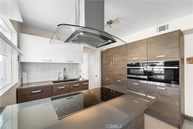 37338 Salem Ct, Palmdale, CA 93550 - kitchen with island range hood, black electric cooktop, tasteful backsplash, dark countertops, and modern cabinets