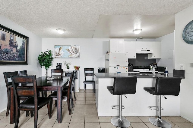 2521 W Sunflower Ave Unit R1, Santa Ana, CA 92704 - kitchen featuring under cabinet range hood, a peninsula, dark countertops, freestanding refrigerator, and white cabinets
