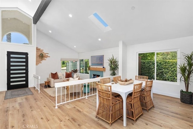 32772 Shipside Dr, Dana Point, CA 92629 - dining area with a skylight, a lit fireplace, light wood-style flooring, high vaulted ceiling, and recessed lighting