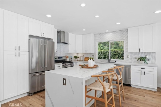 32772 Shipside Dr, Dana Point, CA 92629 - kitchen featuring stainless steel appliances, wall chimney exhaust hood, a kitchen island, light wood-type flooring, and a kitchen bar