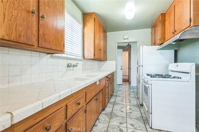 1908 W 134th Pl, Gardena, CA 90249 - kitchen with white gas stove, under cabinet range hood, brown cabinets, and tasteful backsplash
