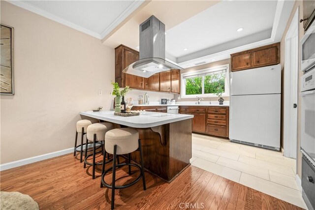 20158 Barnard Ave, Walnut, CA 91789 - kitchen featuring white appliances, island range hood, a peninsula, a breakfast bar, and light countertops