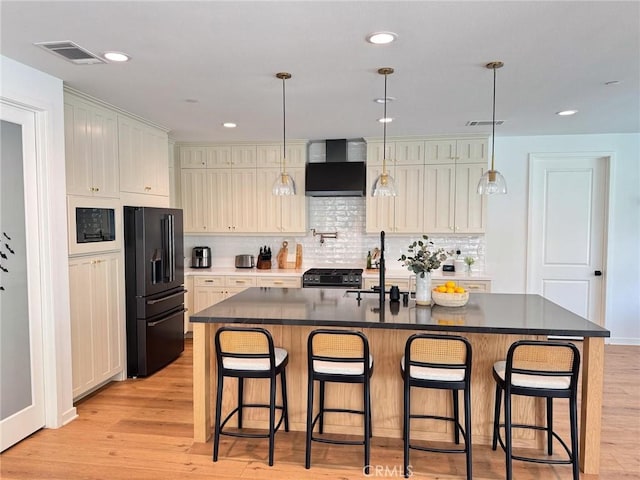 28524 Songbird Way, Saugus, CA 91350 - kitchen with black appliances, wall chimney exhaust hood, dark countertops, light wood-style flooring, and decorative backsplash