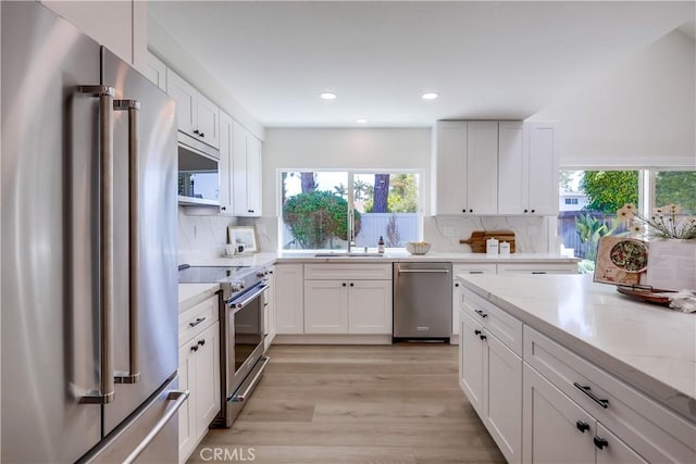 14632 Kimberly Cir, Tustin, CA 92780 - kitchen featuring appliances with stainless steel finishes, light wood-style floors, decorative backsplash, white cabinetry, and recessed lighting