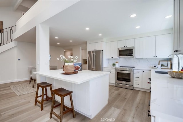 14632 Kimberly Cir, Tustin, CA 92780 - kitchen with high quality appliances, light wood-style flooring, light stone countertops, a kitchen island, and recessed lighting