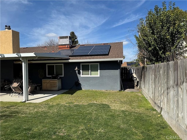 512 E Clinton Ave, Atwater, CA 95301 - rear view of house featuring roof with shingles, a fenced backyard, solar panels, stucco siding, and a patio area