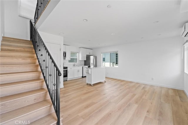 18656 Runnymede St, Reseda, CA 91335 - unfurnished living room featuring stairs, light wood finished floors, and a wall unit AC