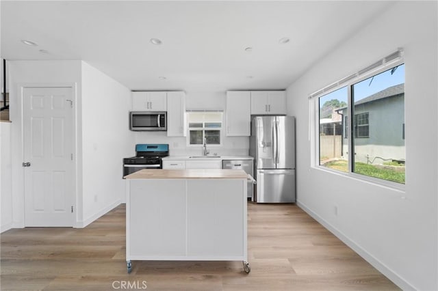 18656 Runnymede St, Reseda, CA 91335 - kitchen with appliances with stainless steel finishes, white cabinets, light countertops, a kitchen island, and light wood-style flooring