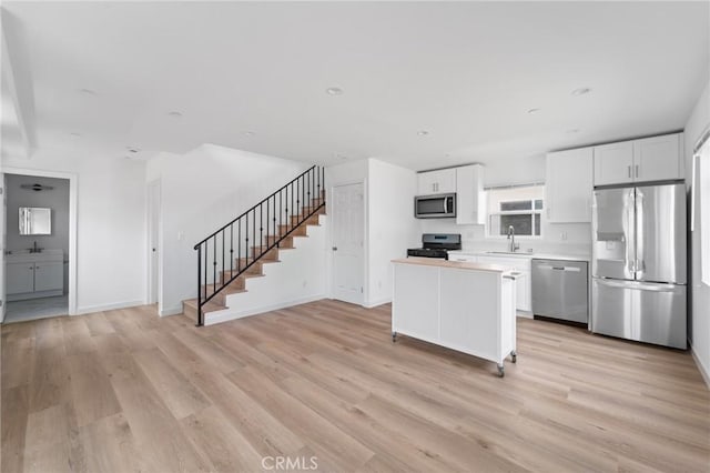 18656 Runnymede St, Reseda, CA 91335 - kitchen with appliances with stainless steel finishes, light wood-type flooring, white cabinetry, a kitchen island, and light countertops