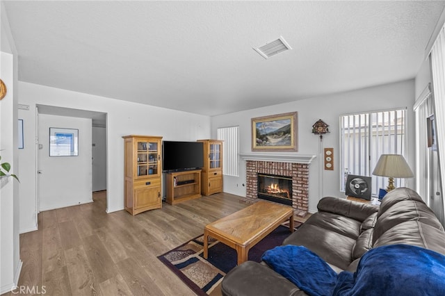 3681 Foxplain Rd, Corona, CA 92882 - living room with plenty of natural light, light wood-type flooring, a textured ceiling, and a fireplace