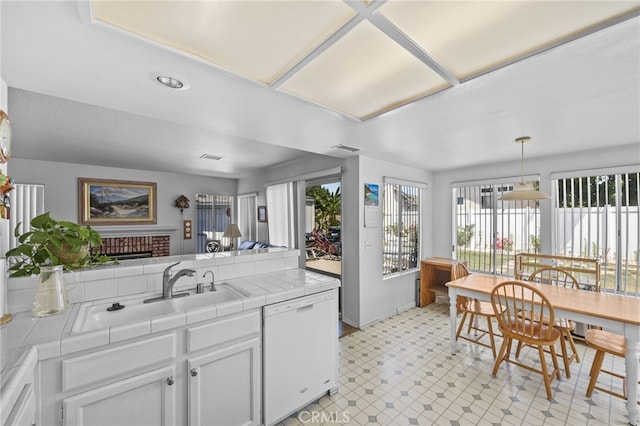 3681 Foxplain Rd, Corona, CA 92882 - kitchen with dishwasher, tile counters, light floors, a brick fireplace, and white cabinets