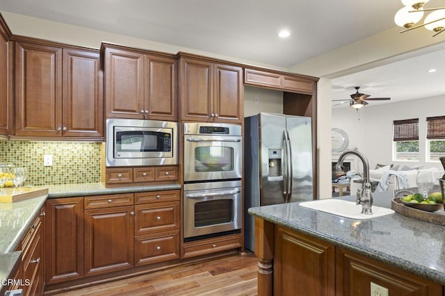 5000 Terramar Way, Oxnard, CA 93035 - kitchen featuring appliances with stainless steel finishes, stone countertops, light wood-style flooring, decorative backsplash, and a ceiling fan