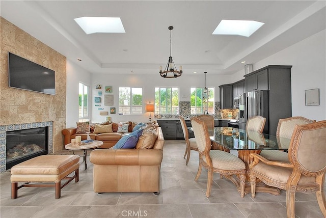 6236 Ashton Pl, Rancho Cucamonga, CA 91739 - living room featuring a skylight, a tray ceiling, light tile patterned floors, a large fireplace, and recessed lighting