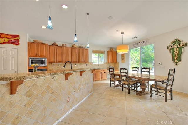 6236 Ashton Pl, Rancho Cucamonga, CA 91739 - kitchen featuring stainless steel microwave, a breakfast bar, wall oven, tasteful backsplash, and recessed lighting