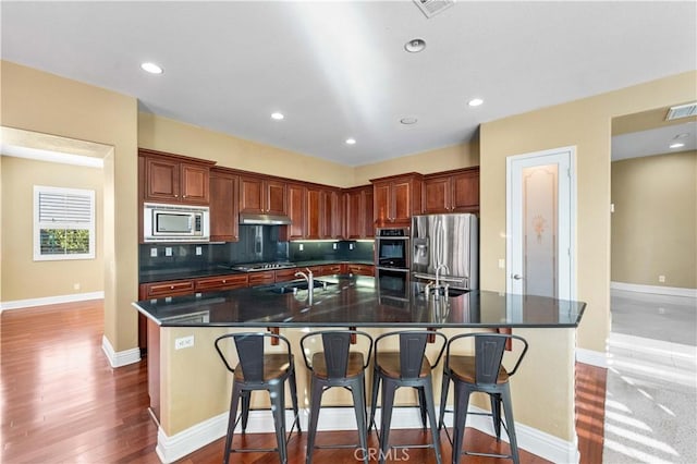 37351 Paintbrush Dr, Palmdale, CA 93551 - kitchen featuring stainless steel appliances, a spacious island, dark countertops, under cabinet range hood, and tasteful backsplash