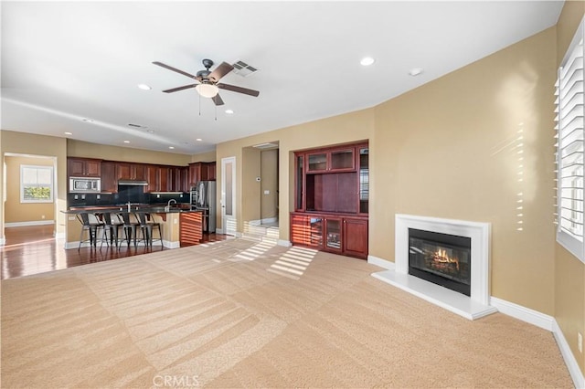 37351 Paintbrush Dr, Palmdale, CA 93551 - living room featuring light colored carpet, ceiling fan, healthy amount of natural light, a glass covered fireplace, and recessed lighting