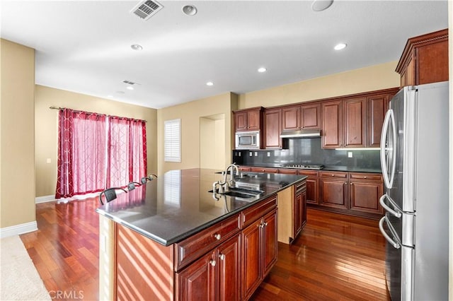 37351 Paintbrush Dr, Palmdale, CA 93551 - kitchen featuring stainless steel appliances, under cabinet range hood, dark wood finished floors, an island with sink, and tasteful backsplash