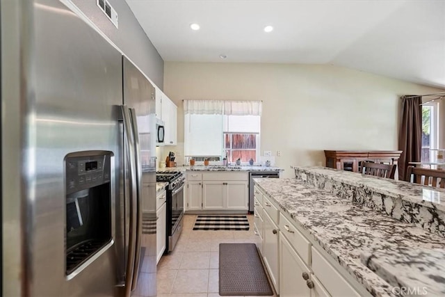 27185 Buffalo Trl, Corona, CA 92883 - kitchen with stainless steel appliances, lofted ceiling, white cabinetry, light stone counters, and light tile patterned floors