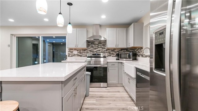 72160 Winters Rd Unit 29, Palms, CA 92277 - kitchen with stainless steel appliances, wall chimney exhaust hood, light wood-style floors, a kitchen island, and tasteful backsplash
