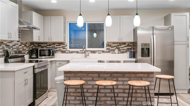 72160 Winters Rd Unit 29, Palms, CA 92277 - kitchen with stainless steel appliances, wall chimney exhaust hood, a breakfast bar area, light countertops, and recessed lighting